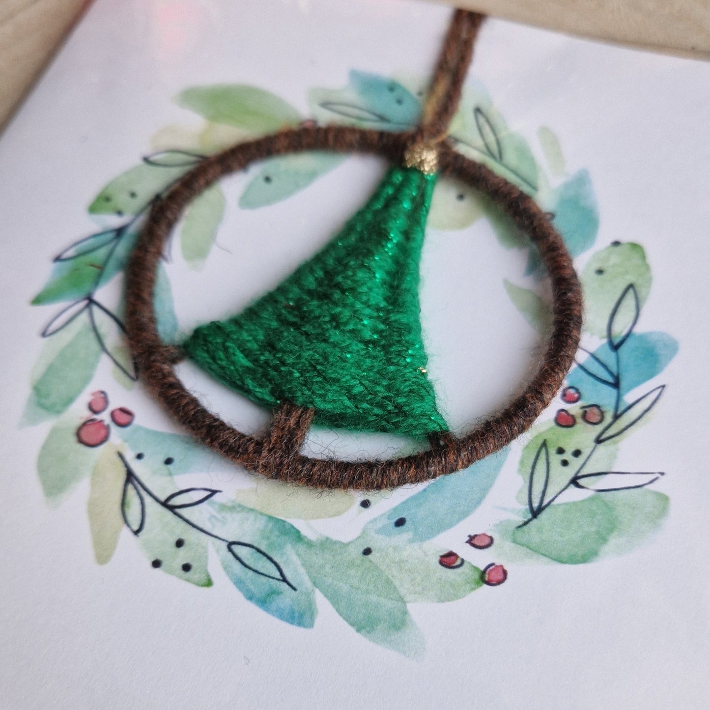 Decorative wreath with green and brown yarn ornament on a white background