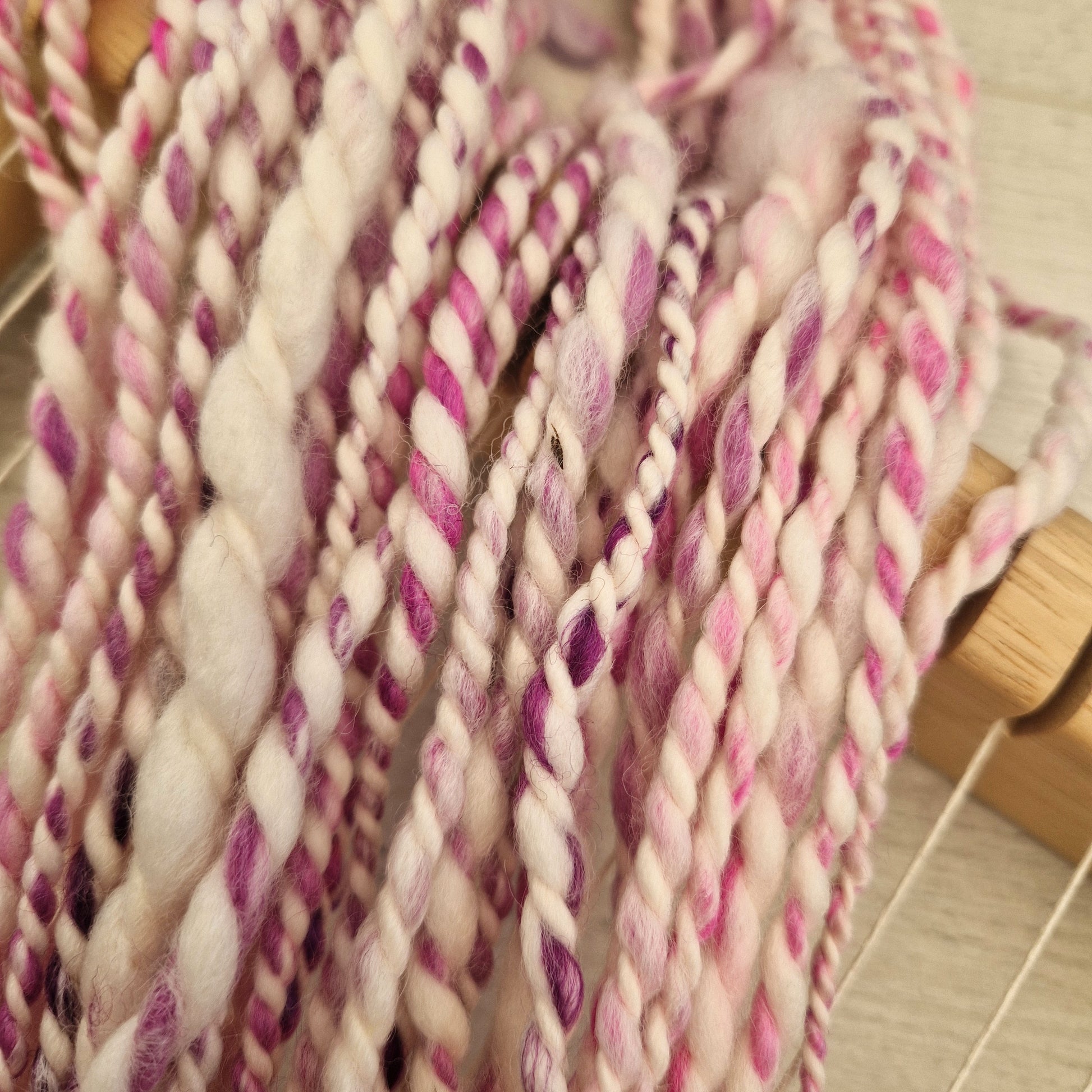 Close-up of pink and white yarn strands on a wooden surface