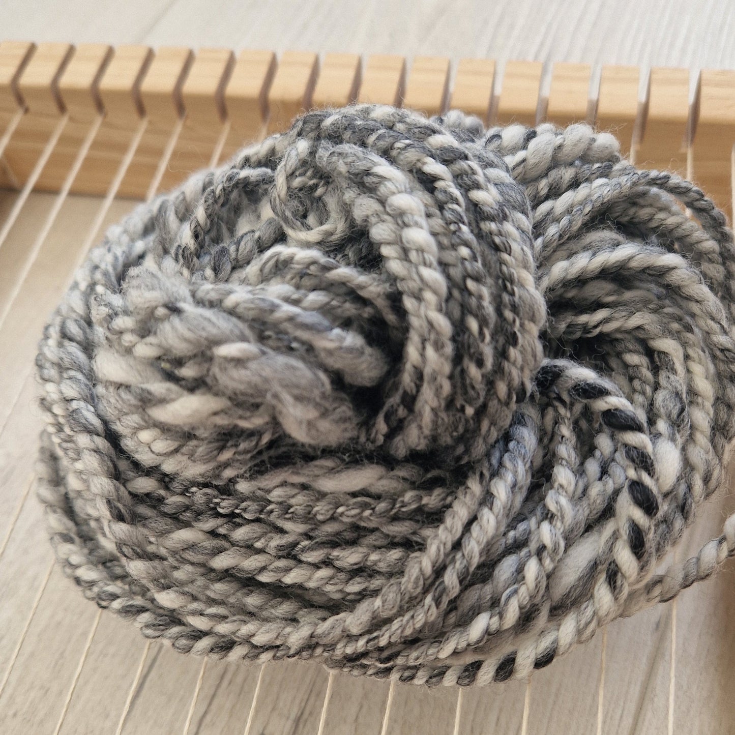 Coiled skein of gray yarn on a wooden surface
