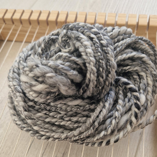 Coiled skein of gray yarn on a wooden surface