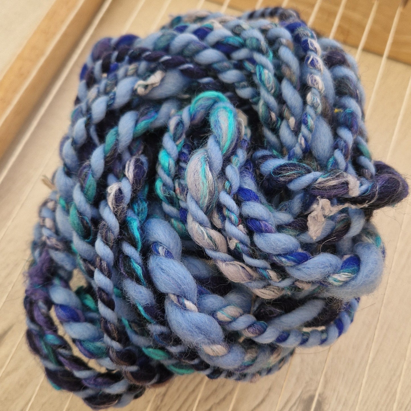Coiled blue chunky yarn on a wooden surface